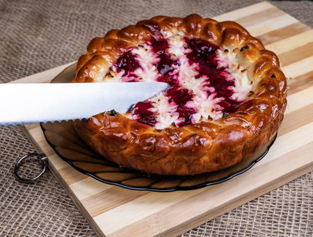Pie with cherries and cottage cheese on a wooden Board and a knife.の写真素材