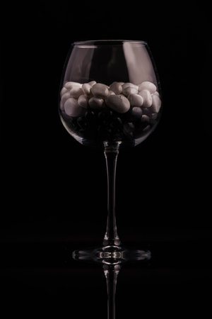Glass on a thin leg with decorative stones on a black background.の写真素材