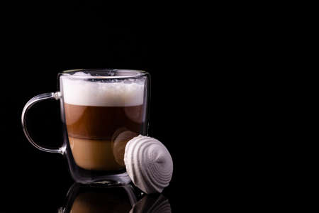 Coffee in a glass cup and marshmallows placed against the cup.の写真素材