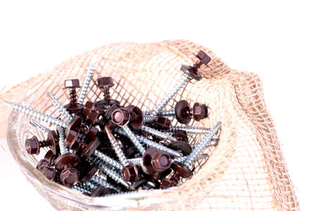 Roofing screws and burlap in a glass container on a white background.の写真素材