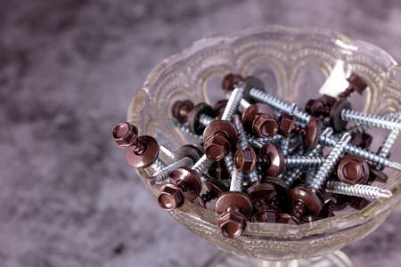 Brown roof screws in glass containers on a gray background.の写真素材