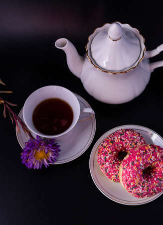 A set of tea ceremony donuts with icing and a flower on a black background.の写真素材