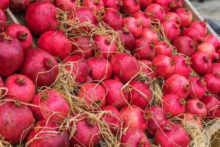 Ripe pomegranate fruits with water droplets on the counter with straw.の写真素材