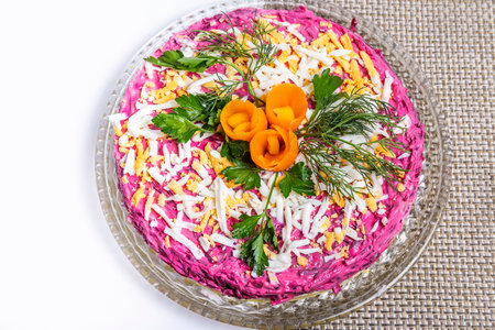 Herring salad under a fur coat on a glass dish with carrot flowers.の写真素材