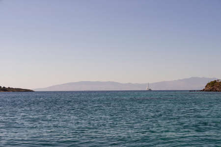 A magnificent landscape with a view of the sea and a lonely yacht on the horizon.の写真素材