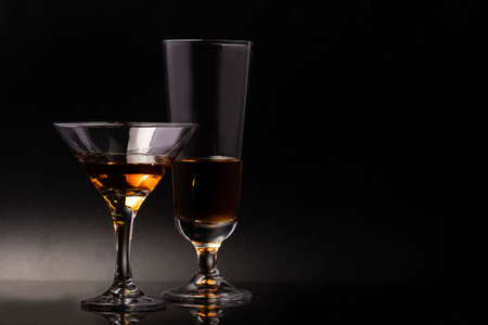 Two glass glasses on a beautiful leg with an alcoholic drink on a black background.の写真素材