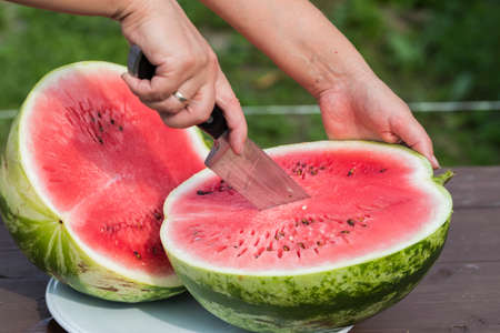 Juicy red watermelon is cut into slices on a wooden table.の写真素材