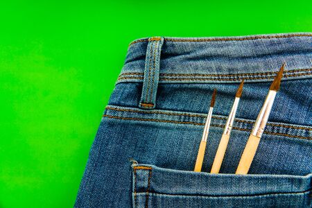 Brushes in the back pocket of blue women's jeans. Concept of a woman artist, designer, creativity, DIY, handmadeの写真素材