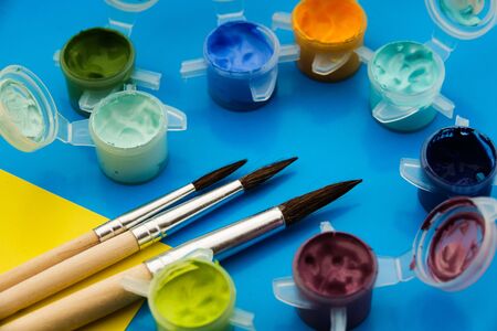 Flat lay composition with different acrilic or oil paints and brushes on blue background.の写真素材