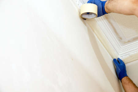 Man plastering a white wall preparing it for painting or wallpapering in a DIY and home decoration.の写真素材