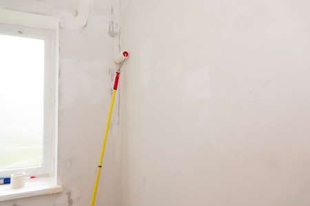Two paint rollers and paint pan with gray paint in room near wall, painting works. Renovation and construction works at room in flat, apartment, house. Prepared tools for work.の写真素材
