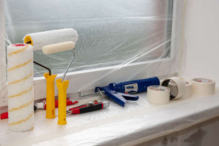 Two paint rollers and paint pan with gray paint in room near wall, painting works. Renovation and construction works at room in flat, apartment, house. Prepared tools for work.の写真素材