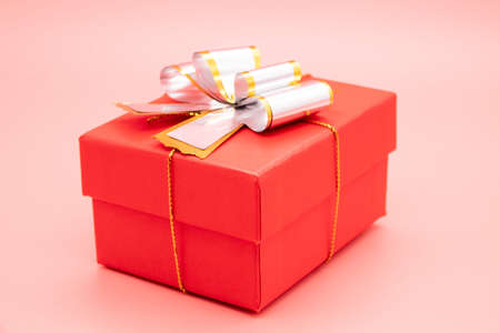 Red gift box with white ribbon and presents on pinkの写真素材