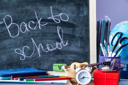 wooden plaque with the inscription back to school near stationery on a brown wooden