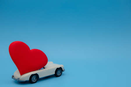 White retro toy car delivering a bouquet of flowers on a pink background. Postcard February 14, Valentine's Day. Flower delivery. March 8, International Happy Women'sの写真素材