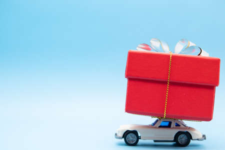 White retro toy car delivering a bouquet of flowers on a pink background. Postcard February 14, Valentine's Day. Flower delivery. March 8, International Happy Women'sの写真素材
