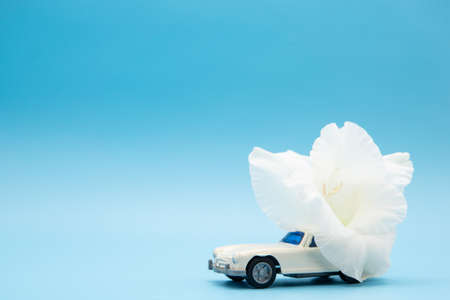 White retro toy car delivering a bouquet of flowers on a pink background. Postcard February 14, Valentine's Day. Flower delivery. March 8, International Happy Women'sの写真素材