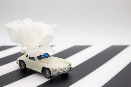 White retro toy car delivering a bouquet of flowers on a black and white background. Postcard February 14, Valentine's Day. Flower delivery. March 8, International Happy Women'sの写真素材
