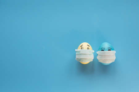 Eggs with smiling eyes and green medical or hygienic mask on wood background, Preparing for protection children from virus pestilence on Easter day conceptの写真素材