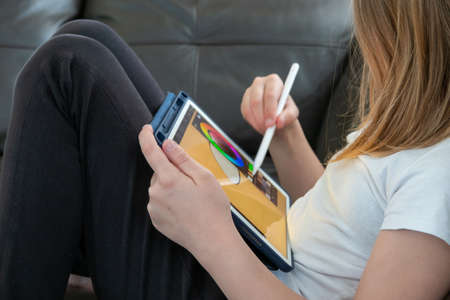 Girl digital artist draws with a stylus on a tablet or laptop. She is a student and is studying...