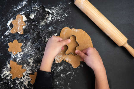 Children's hands make New Year's gingerbread cookies on a wooden table. New Year and Christmas concept.の写真素材