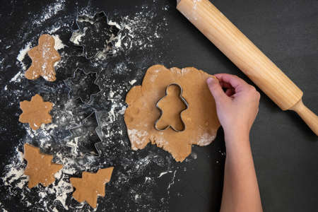 Children's hands make New Year's gingerbread cookies on a wooden table. New Year and Christmas concept.の写真素材