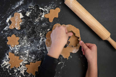 Children's hands make New Year's gingerbread cookies on a wooden table. New Year and Christmas concept.の写真素材