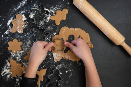 Children's hands make New Year's gingerbread cookies on a wooden table. New Year and Christmas concept.の写真素材