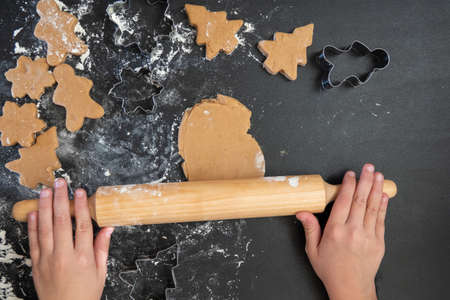 Children's hands make New Year's gingerbread cookies on a wooden table. New Year and Christmas concept.の写真素材