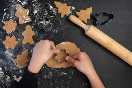 Children's hands make New Year's gingerbread cookies on a wooden table. New Year and Christmas concept.の写真素材