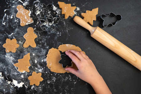 Children's hands make New Year's gingerbread cookies on a wooden table. New Year and Christmas concept.の写真素材
