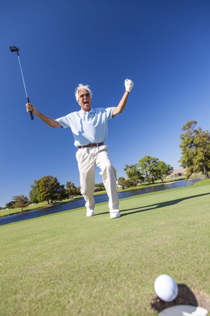 Senior man male golfer celebrating successful put on the green of a golf courseの写真素材