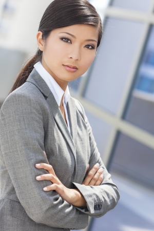 Outdoor portrait of a beautiful young Asian Chinese woman or businesswoman in smart business suitの写真素材