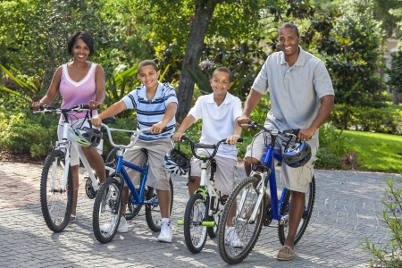 A young African American family, woman, man, father, mother & twosons  boy children riding bicycles...