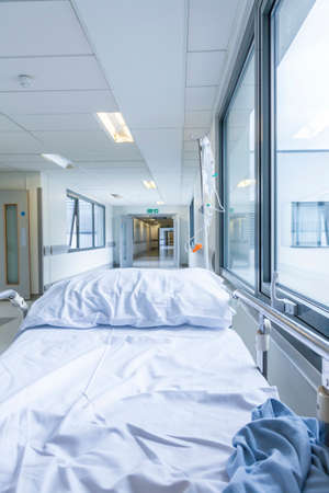 Bereavement, death or loss concept shot of empty bed, gurney or stretcher with drip in hospital corridorの写真素材