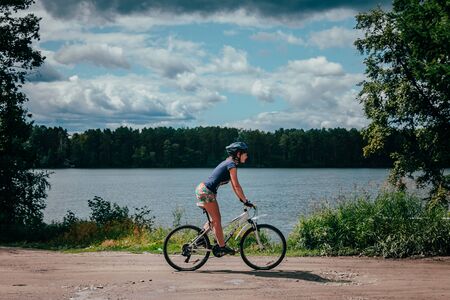 Miass, Russia - July 19, 2015: girl mountainbiker rides along the lake during race "Clean water-2015", Miass, Russia - July 19, 2015のeditorial素材