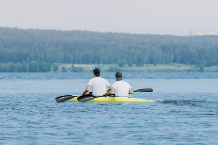 Two boys in sport kayak paddles on the waterの写真素材