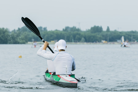 Two boys in sport kayak paddles on the waterの写真素材