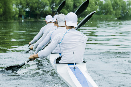 four boys in sport kayak paddles on the waterの写真素材