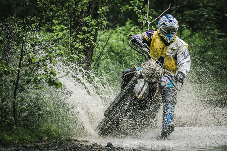 Kyshtym, Russia - June 21, 2015: Motocross driver under the spray of water competes during the race Urals Cup of Enduro "Stone belt 2015", Kyshtym, Russia - June 21, 2015のeditorial素材