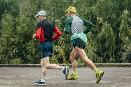 Omsk, Russia -  September 20, 2015: two elderly athlete run along river during Siberian international marathonのeditorial素材