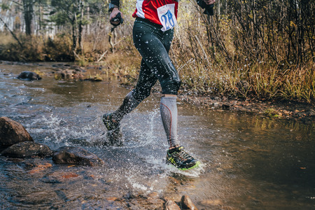 Beloretsk, Russia -  September 26, 2015: feet closeup male runner crossing river on rocks during marathon mountain "Big Iremel"のeditorial素材
