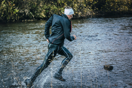 Beloretsk, Russia -  September 26, 2015: male athlete crossing the river on rocks side view during marathon mountain "Big Iremel"のeditorial素材