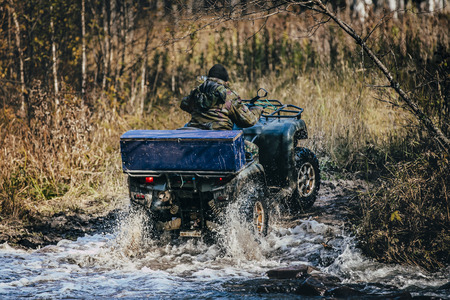Forester ATV rides through autumn forest through a river crossingの写真素材