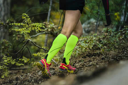 closeup slender and beautiful legs of woman running  in compression socks. fitness and exercise in forestの写真素材