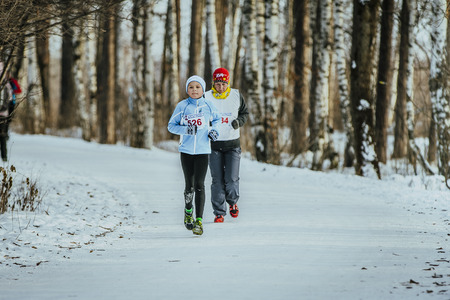 Ekaterinburg, Russia - November 14, 2015: grandson and his grandmother running through winter woods together during Urban winter marathonのeditorial素材
