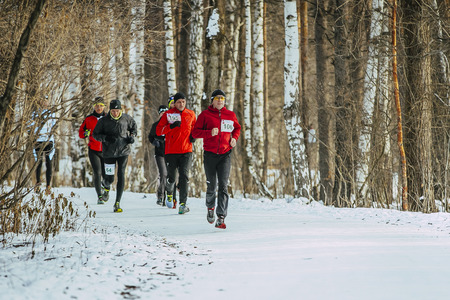 Ekaterinburg, Russia - November 14, 2015: General plan of running on a snowy road in forest group men athletes closeup during Urban winter marathonのeditorial素材