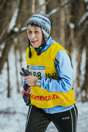 Ekaterinburg, Russia - November 14, 2015: elderly looking woman athlete running on snowy road in forest during Urban winter marathonのeditorial素材