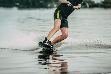 male athlete rides on a wakeboard on lake in summerの写真素材