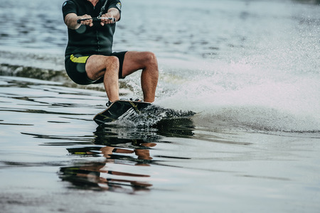 male athlete rides on a wakeboard wave. summer lakeの写真素材